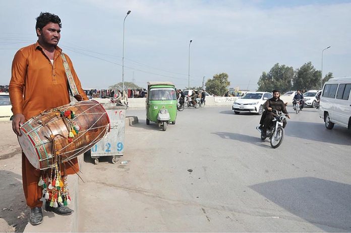 A drum beater is waiting for the customers to get hired for earning some livelihood at a roadside