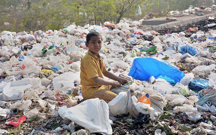 A gypsy child searching valuables from the heap of garbage