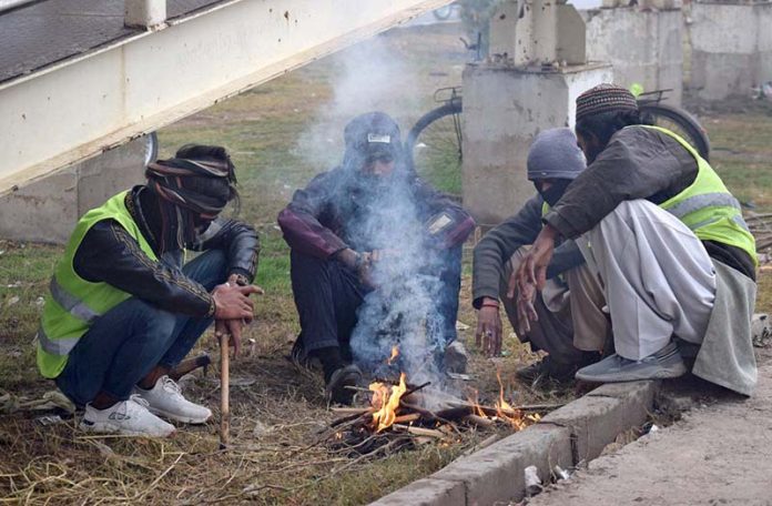 People sitting around the fire to keep them warm in cold weather