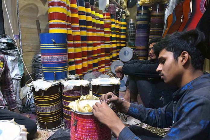 Workers busy in preparing the traditional musical instrument Drums (Dhoolke) for sale at his shop.