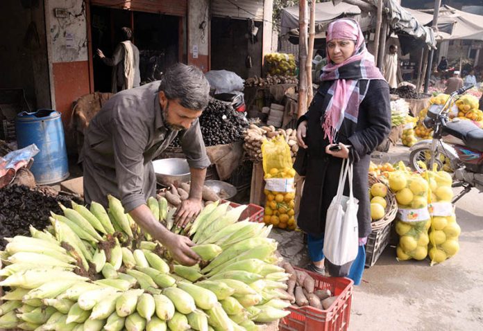 Vendor selling corn cobs at his shop to attract the customers at Baghbanpura