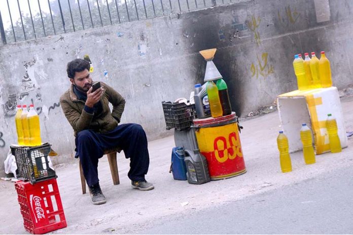 A vendor waiting for customers to sell petrol at his roadside setup