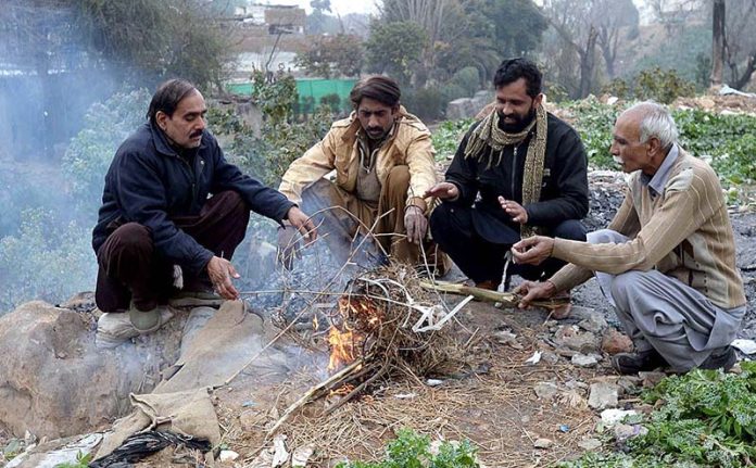 People sitting around fire to keep themselves warm during cold weather