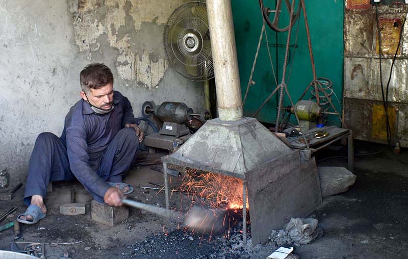 A view of Blacksmith preparing saw at his work place