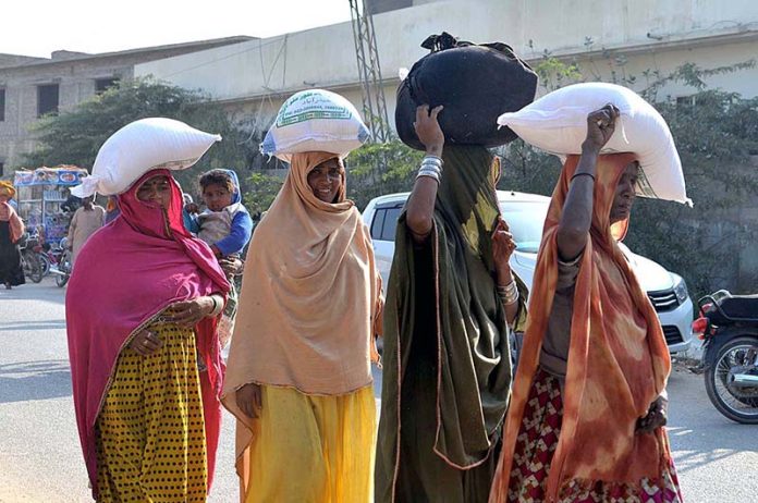 Women going back home after purchased subsidized flour from a delivery truck near Niaz Stadium