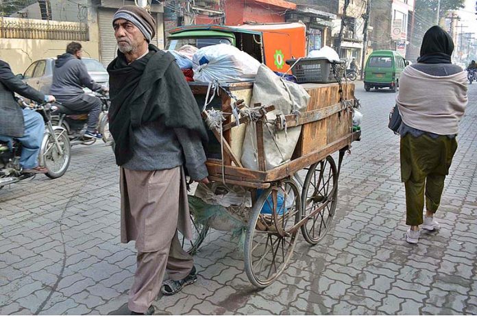 An old man vendor pulling his cart moving towards his destination