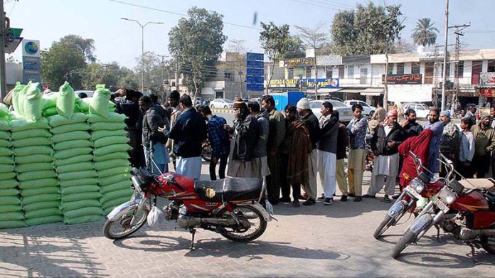 People are standing in a long queue to purchase flour bags on subsidized rate by the provincial government at the Square Fawara Bahawalpur