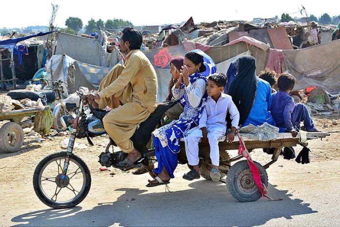 Family traveling on a tri-cycle rickshaw at Latifabad