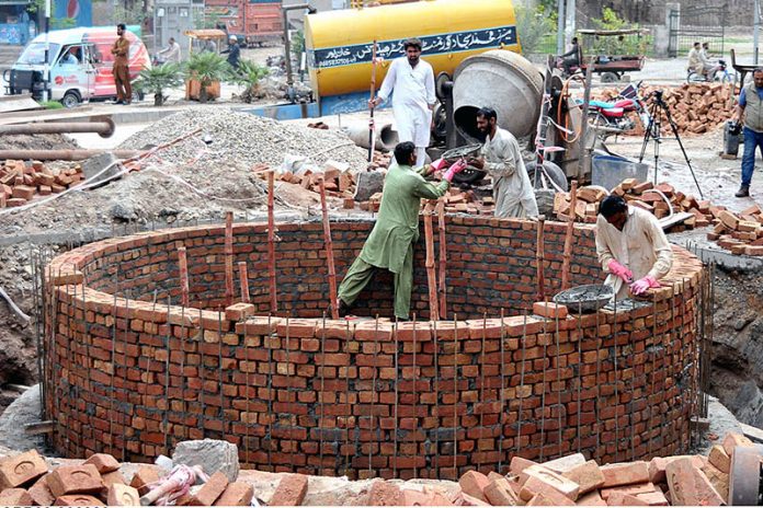 Labourers busy in construction work of sewer manhole at Water Works Road.