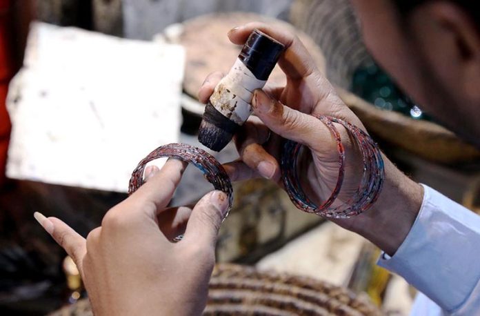 Workers giving final touches to bangles at their workplace at bangle market