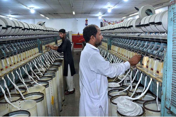 Workers busy in operating a spinning unit for the production of cotton yarn from cotton fiber at a local factory