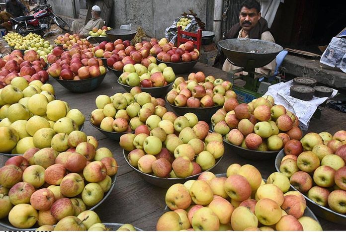 A vendor waiting for customers to sell Apples on his hand cart at fruit and vegetable market