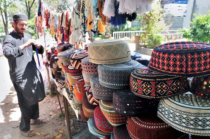 A vendor arranging and displaying caps to attract the customers outside masjid at Aabpara during holy month of Ramzan