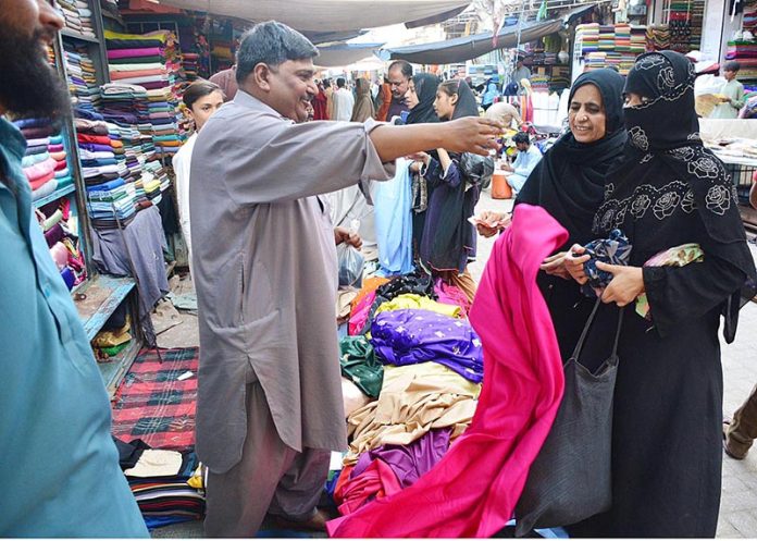 Families are selecting and purchasing clothes at the Cloth Market in preparation for the upcoming Eid-al-Fitr.