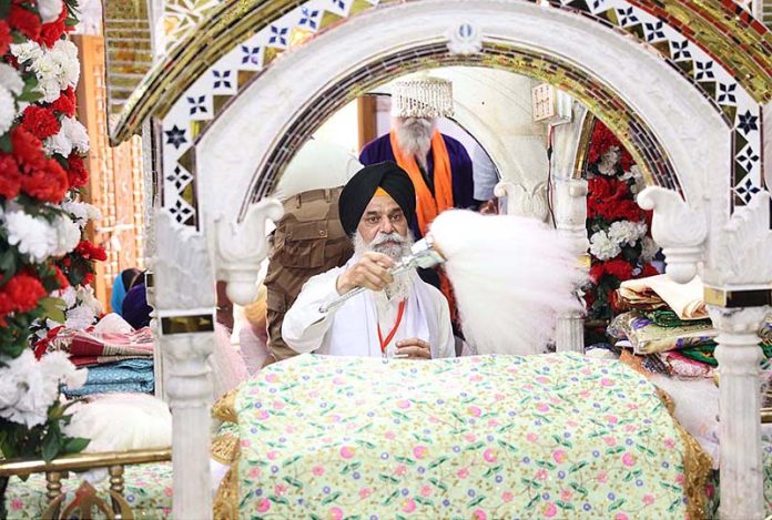 An elder Granthi waving the chauri ( Horse hair fan) over the Guru Granth Sahib during the annual Baisakhi harvest festival, with the main ceremony of the New Year's celebration of Sikh community at their Holy Shrine Panja Sahib in Hasan Abdal.