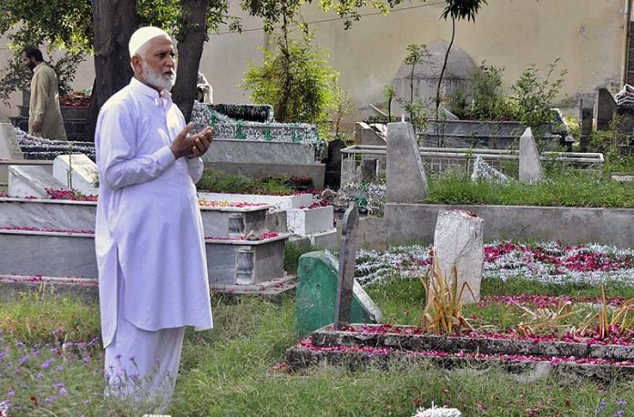 A person offering fateha on the grave of his family member on the occasion of Eidul Fitr