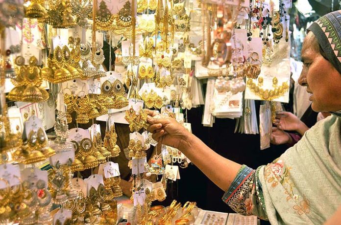 A woman selecting and purchasing jewelry for upcoming Eid ul Fitr festival at Urdu bazar.