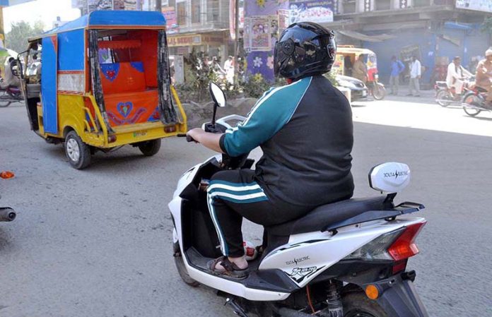 woman riding an electric scooter due to unaffordable petroleum products at city road.APP/