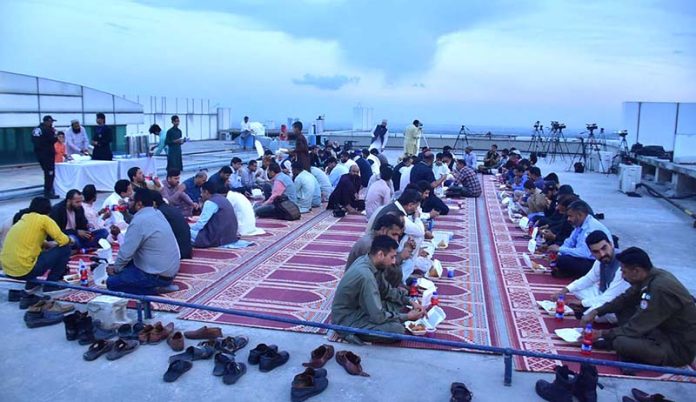 Members of Central Ruet-e-Hilal Committee along with media personnel breaking their fast on the eve of Shawal moon sighting on the rooftop of Religious Affairs building