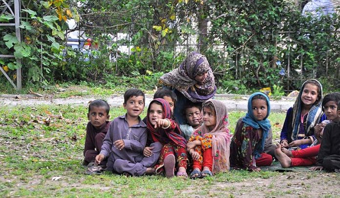 A group of gypsy children siting at a roadside greenbelt in Federal Capital