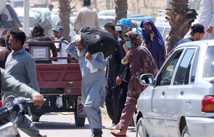 People on the way crossing a busy road at Pirwadhai Bus Terminal in the city