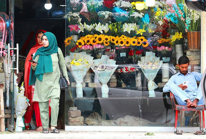 A vendor displaying bouquet of flowers at his shop to attract customers at Jinnah Super Market