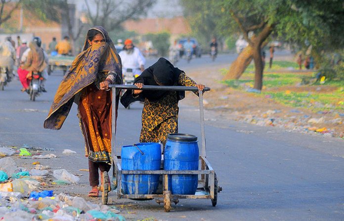 Gypsy girls pushing hand cart carrying water pots after filling from the filtration plant