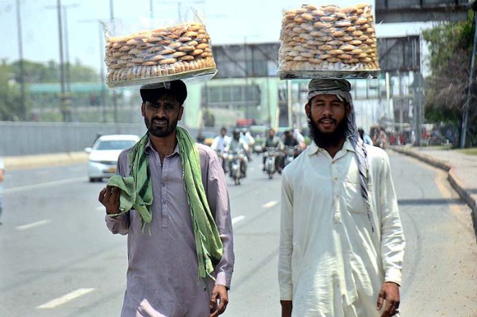 Vendors selling naan khatai while shuttling on the road at Ferozepur Road in the Provincial Capital