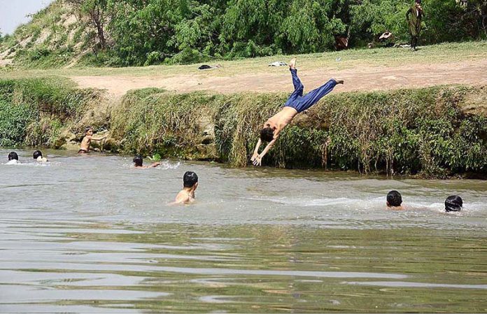 Youngsters diving in a canal for swimming to get relief from hot weather near Musazai area