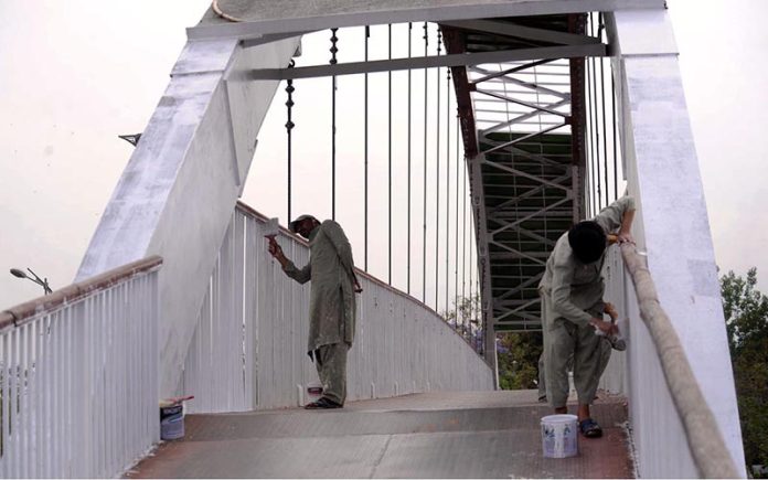 Painter paints on the grill of 7th Avenue flyover in Federal Capital