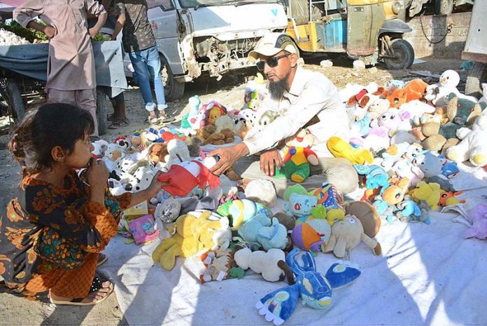 A child watching a vendor selling toys at a roadside stall