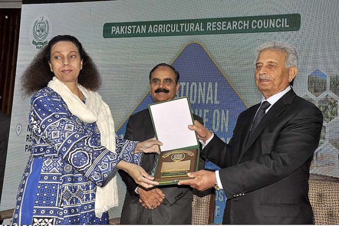 Federal Minister for Education and Professional Training Rana Tanveer Hussain giving a shield to a female participant at 3-day seminar on 