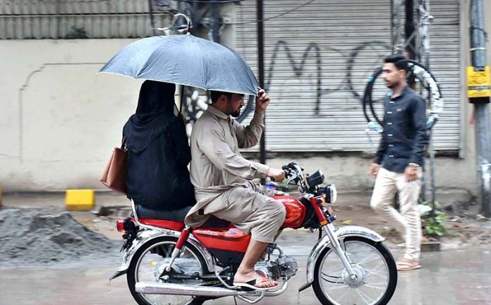 A woman holding an umbrella to protect from rain on motorcycle in the city