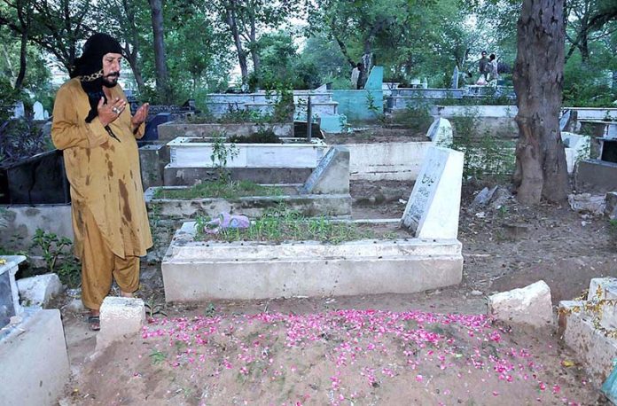 People reciting Holy Quran and offering fateha on the graves of their ...