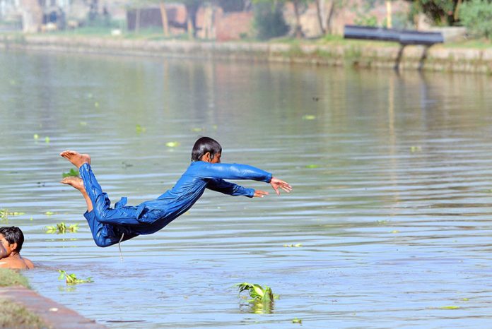 A youngster jumping and bathing in the canal to get relief from the hot weather in the city