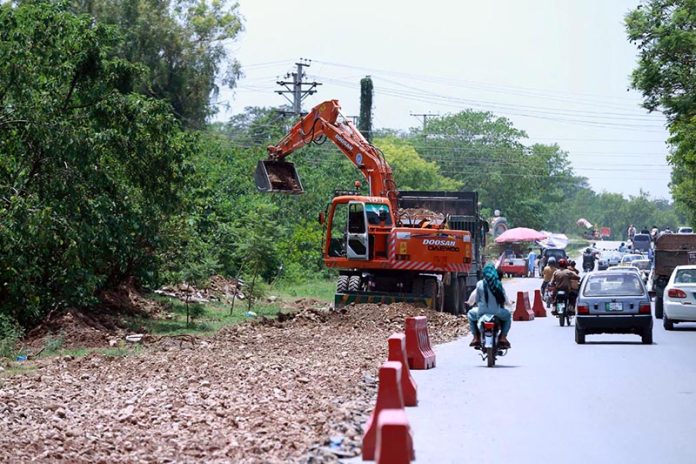 Heavy machinery being used to a expand a road at Chak Shahzad neighbourhood in the Federal Capital