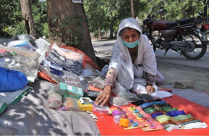 A female vendor selling various religious items on the side of the I-10 Markaz Road