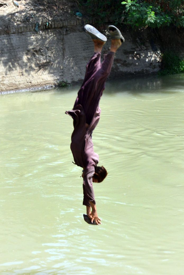 Youngster jumping into the canal to get some relief from hot weather in the city