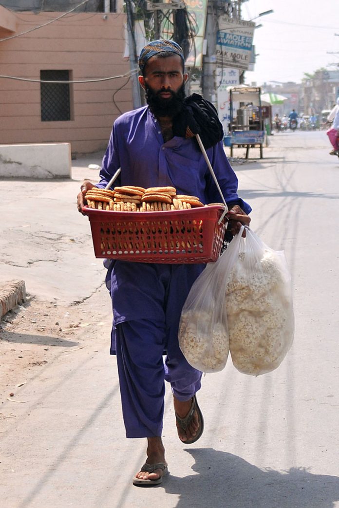 A street vendor selling edible items while shuttling on the road