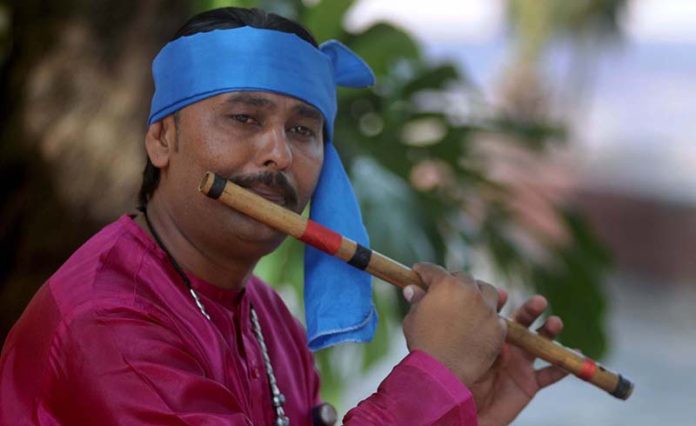 Artist plays his musical instrument flute to attract people during Saqafati Mela at Lok Virsa