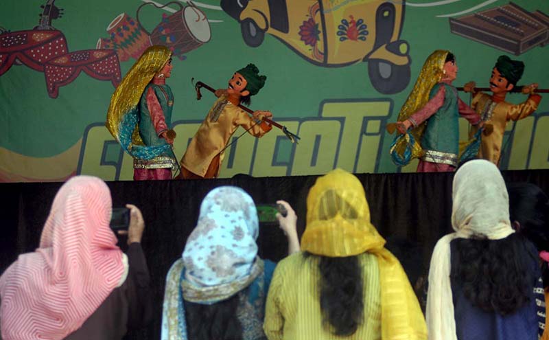 Artist plays his musical instrument flute to attract people during Saqafati Mela at Lok Virsa