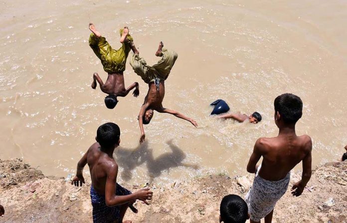 Youngsters jumping into the canal to beat the heat during hot weather in the city