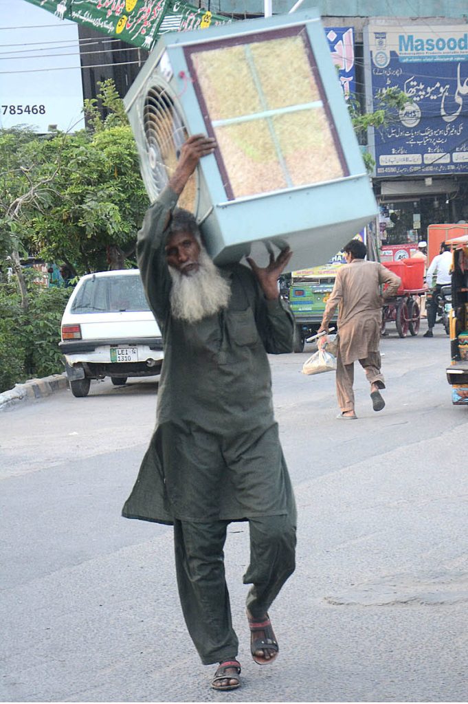 A man carrying air cooler on his shoulder