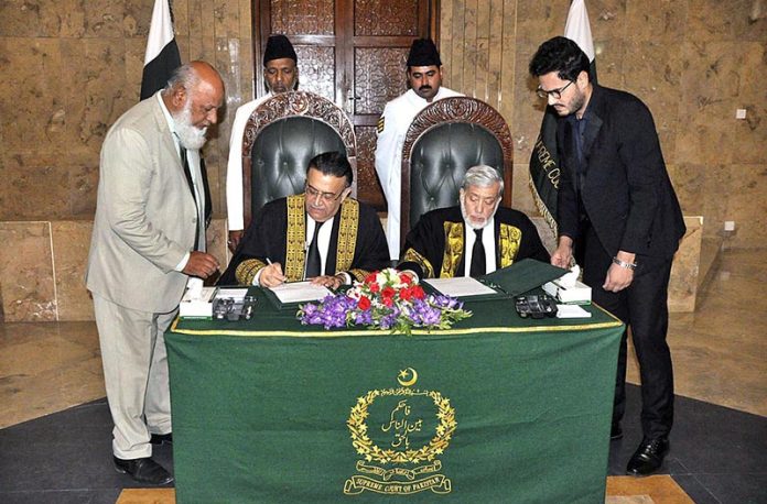 Honourable Mr. Justice Umar Ata Bandial, Chief Justice of Pakistan signing after administering the oath of office to Honourable Mr. Justice Iqbal Hameed-ur-Rehman, former Judge of the Supreme Court of Pakistan, as Chief Justice of the Federal Shariat Court at Supreme Court of Pakistan