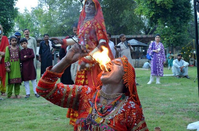 A folk artist from Cholistan blowing fire from mouth during Saqafati Mela at Lok Virsa