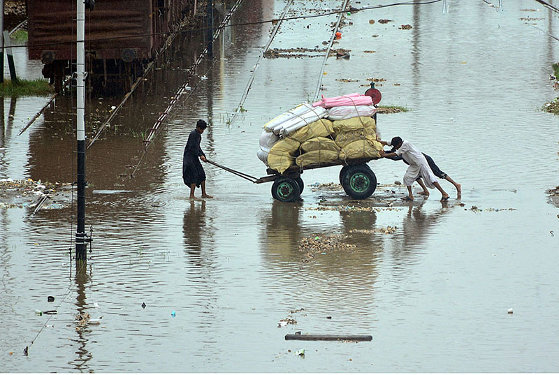 People passing through rain water accumulated at Railway Colony area after heavy rain in the city