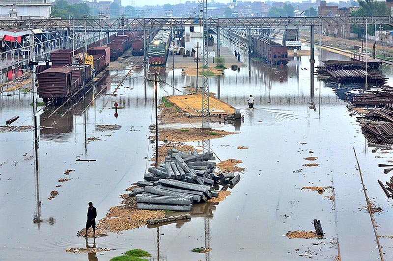 People passing through rain water accumulated at Railway Colony area after heavy rain in the city