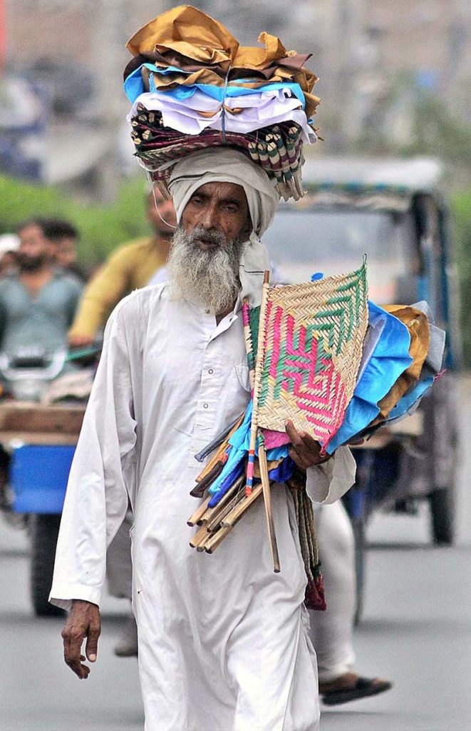 An elder vendor selling traditional handmade fans while shuttling on Masoom Shah Road