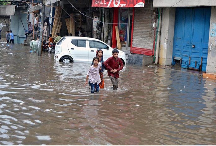 Children wading through water accumulated in Lakshmi Chowk due to heavy rain