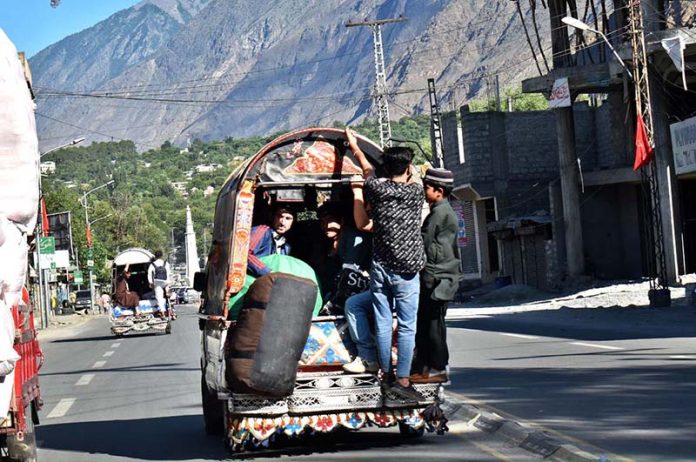 People hanging on passenger van in risky way may cause any mishap, needs the attention of concern authorities.